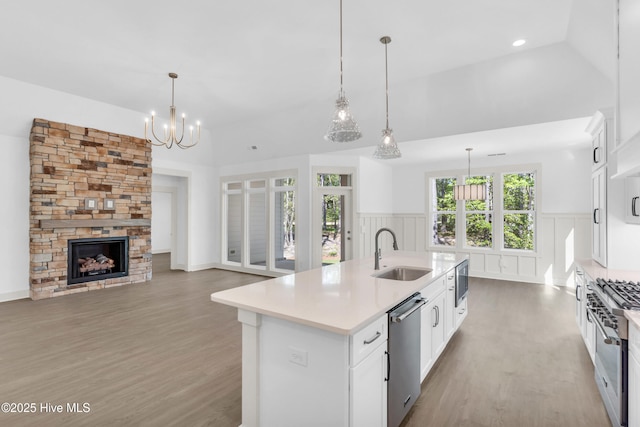 kitchen featuring wood finished floors, a sink, an island with sink, light countertops, and appliances with stainless steel finishes