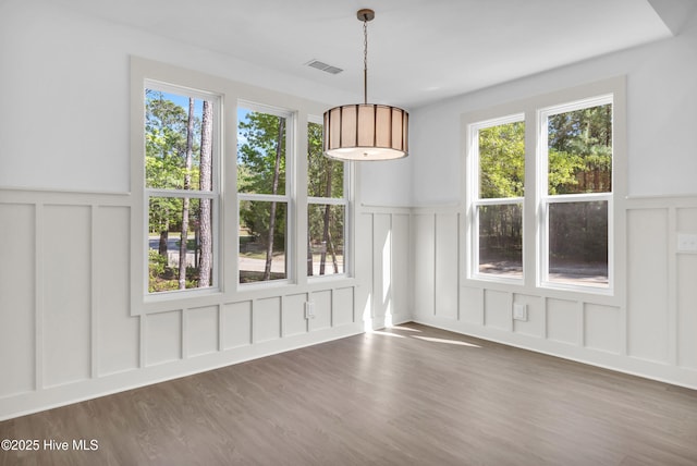 unfurnished dining area featuring a decorative wall, a wainscoted wall, and visible vents