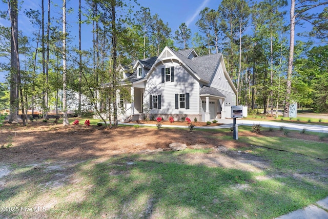 view of front facade featuring a front lawn, a shingled roof, and covered porch