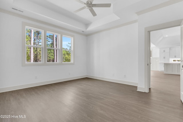 unfurnished room featuring wood finished floors, visible vents, a raised ceiling, and ceiling fan