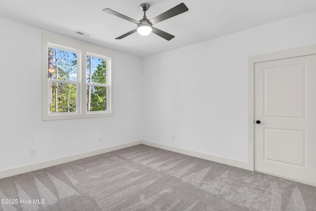carpeted spare room with visible vents, baseboards, and ceiling fan