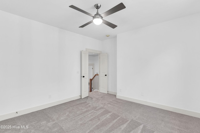 empty room featuring a ceiling fan, baseboards, and carpet