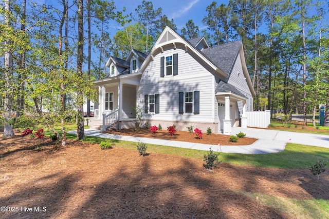 view of front of property featuring roof with shingles, concrete driveway, covered porch, a garage, and fence