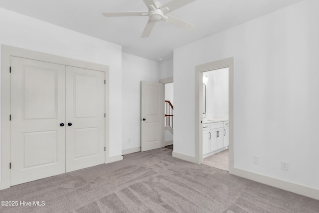 unfurnished bedroom with a ceiling fan, light carpet, a closet, baseboards, and ensuite bathroom