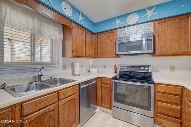 kitchen featuring sink, stainless steel appliances, a textured ceiling, and light hardwood / wood-style flooring