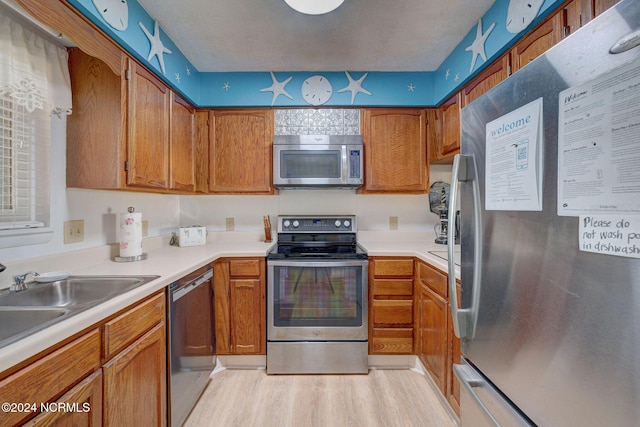 1000 Caswell Beach Rd Unit 1111, Oak Island, NC 28465 - kitchen featuring appliances with stainless steel finishes, brown cabinets, light wood-type flooring, and a sink