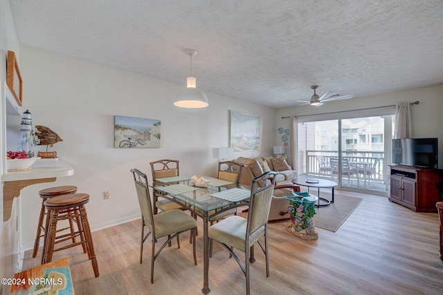 dining space with light hardwood / wood-style floors, a textured ceiling, and ceiling fan