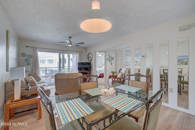 living room with light hardwood / wood-style flooring, a textured ceiling, and ceiling fan