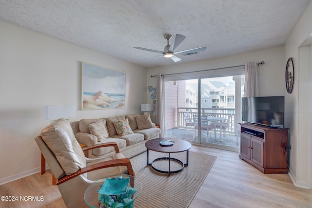 living room featuring light hardwood / wood-style flooring, a textured ceiling, and ceiling fan