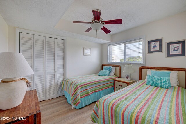 bedroom with a closet, ceiling fan, a textured ceiling, and light hardwood / wood-style flooring