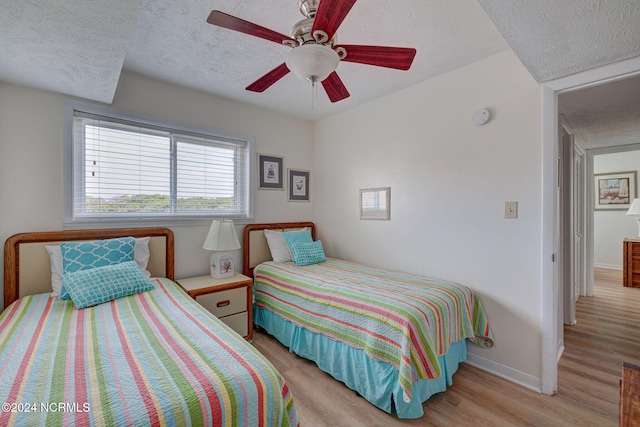 bedroom with a textured ceiling, light hardwood / wood-style floors, and ceiling fan