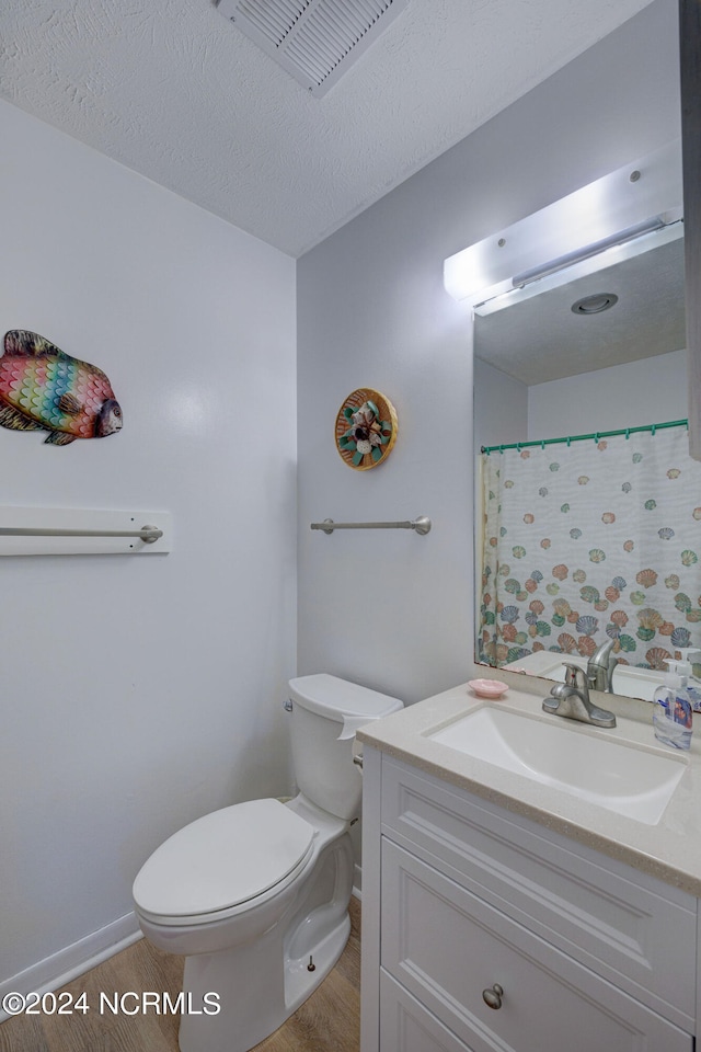 bathroom featuring vanity, toilet, a textured ceiling, and hardwood / wood-style floors