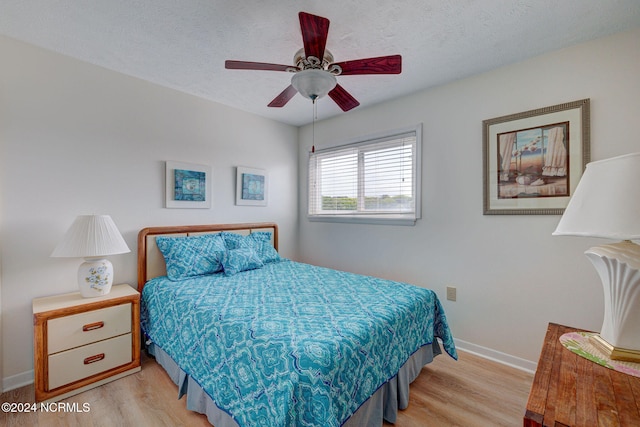 bedroom with a textured ceiling, light hardwood / wood-style floors, and ceiling fan