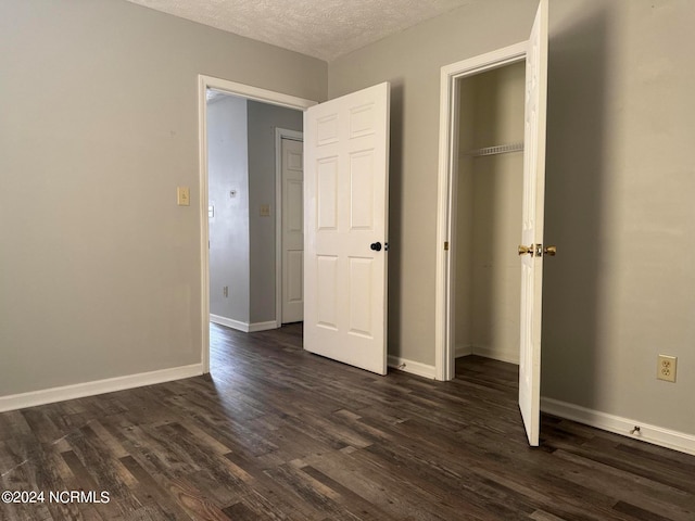 unfurnished bedroom featuring a textured ceiling, a closet, and dark hardwood / wood-style flooring