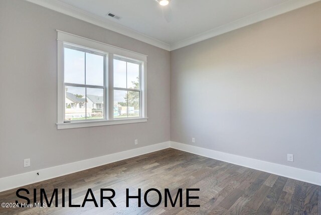 empty room with crown molding, wood finished floors, and baseboards