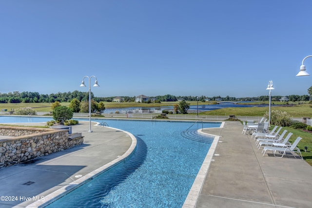 view of pool with a water view and a patio area