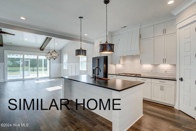 kitchen featuring high end black refrigerator, a sink, white cabinetry, open floor plan, and dark countertops