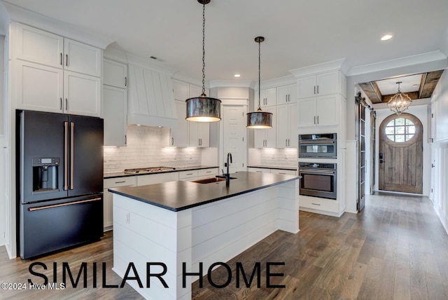 kitchen featuring an island with sink, dark countertops, high quality fridge, white cabinetry, and a sink