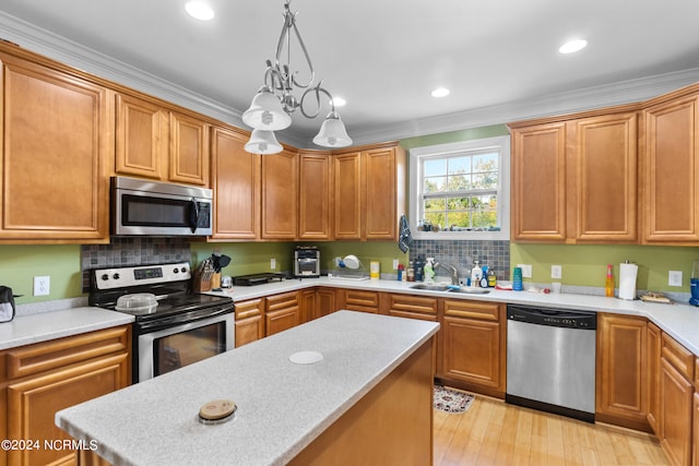 kitchen featuring light hardwood / wood-style flooring, hanging light fixtures, crown molding, sink, and appliances with stainless steel finishes