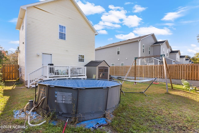 rear view of property with a storage unit, a lawn, and a fenced in pool