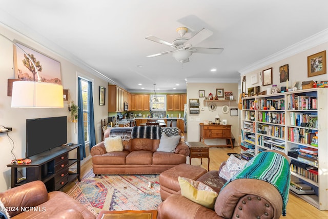 living room featuring ornamental molding, light wood-type flooring, and ceiling fan