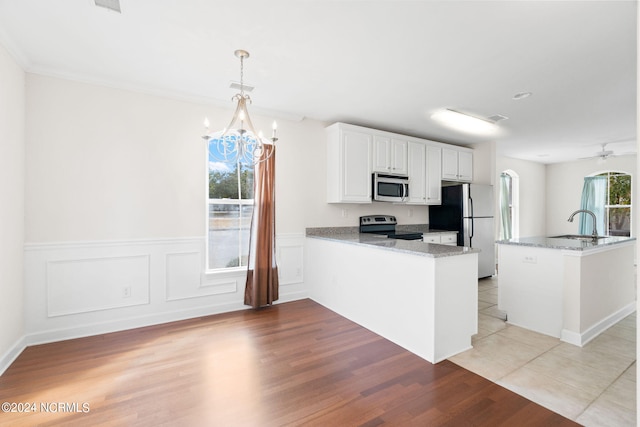 kitchen featuring hanging light fixtures, kitchen peninsula, white cabinetry, appliances with stainless steel finishes, and light hardwood / wood-style floors