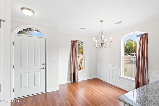 entrance foyer featuring ornamental molding, hardwood / wood-style floors, and an inviting chandelier