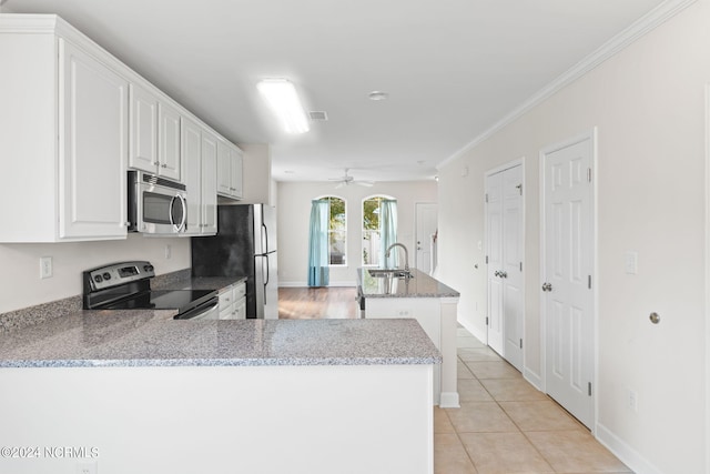 kitchen with white cabinets, light tile patterned floors, appliances with stainless steel finishes, light stone countertops, and crown molding