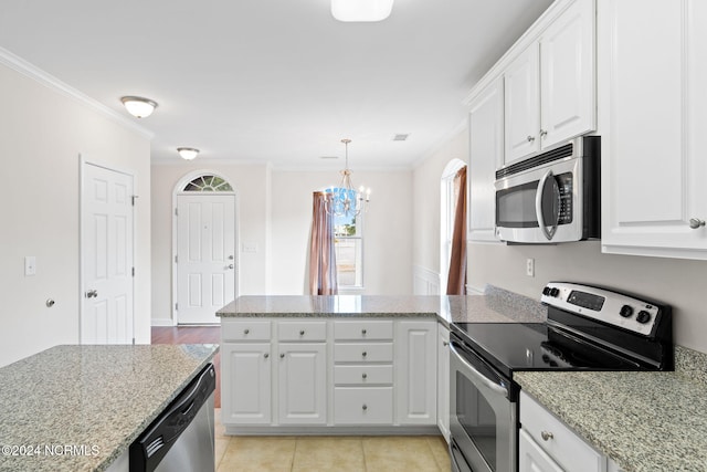 kitchen with appliances with stainless steel finishes, white cabinets, light stone counters, and ornamental molding