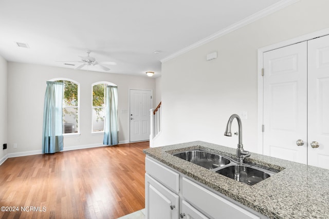 kitchen with light hardwood / wood-style flooring, white cabinets, light stone countertops, and crown molding