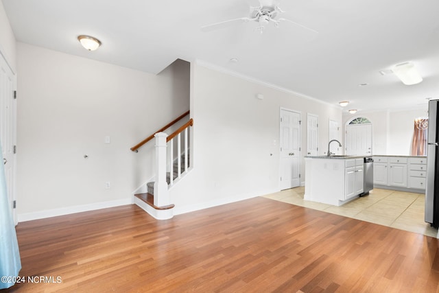 kitchen with white cabinetry, sink, light wood-type flooring, and a kitchen island with sink