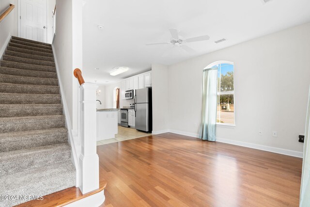 unfurnished living room featuring light wood-type flooring and ceiling fan