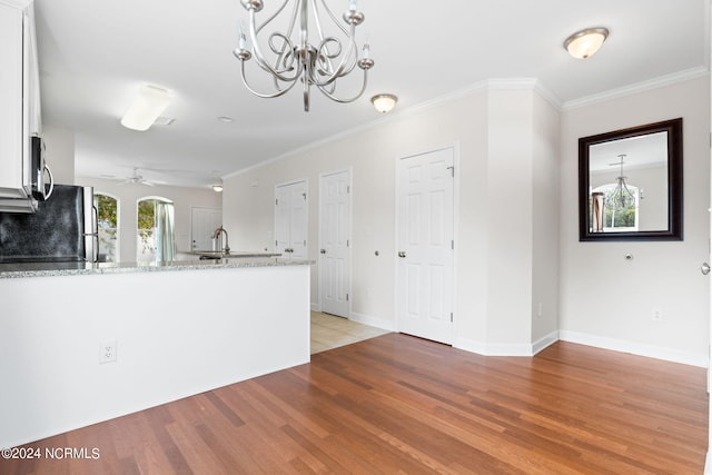 kitchen featuring white cabinetry, light stone counters, stainless steel appliances, and light wood-type flooring