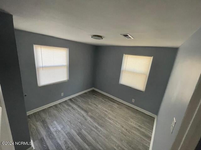 spare room featuring dark hardwood / wood-style floors and vaulted ceiling