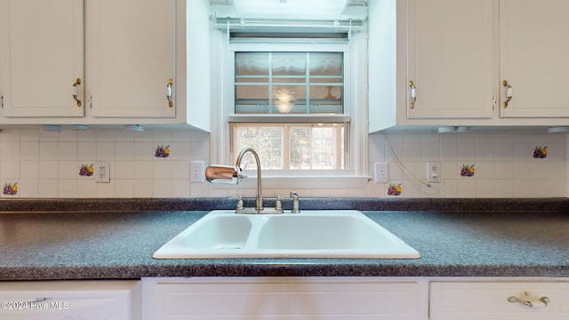 kitchen featuring backsplash, sink, white dishwasher, and white cabinets