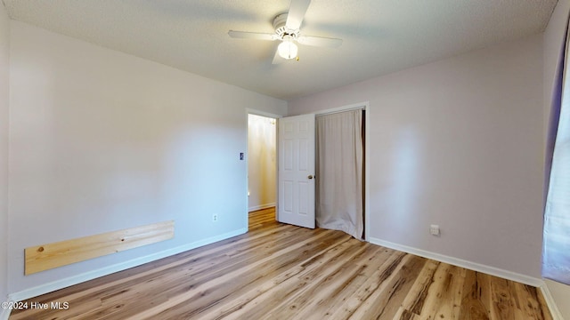 unfurnished bedroom featuring a closet, light hardwood / wood-style floors, a textured ceiling, and ceiling fan