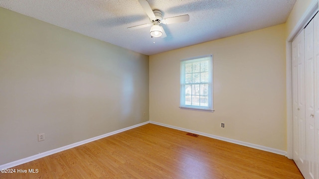 unfurnished bedroom with ceiling fan, a textured ceiling, a closet, and light hardwood / wood-style flooring