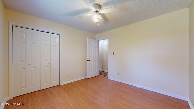 unfurnished bedroom with a textured ceiling, light hardwood / wood-style flooring, ceiling fan, and a closet