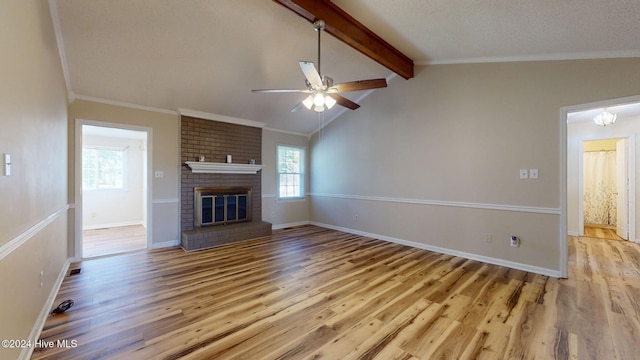 unfurnished living room featuring vaulted ceiling with beams, crown molding, light wood-type flooring, a brick fireplace, and ceiling fan