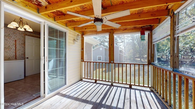 unfurnished sunroom featuring ceiling fan with notable chandelier