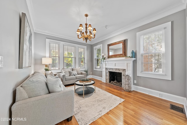 living room featuring a premium fireplace, crown molding, an inviting chandelier, and hardwood / wood-style flooring