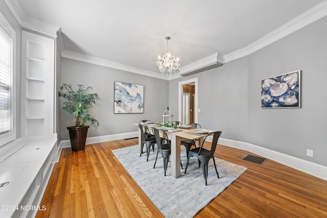 dining room featuring a chandelier, light hardwood / wood-style floors, built in features, and crown molding