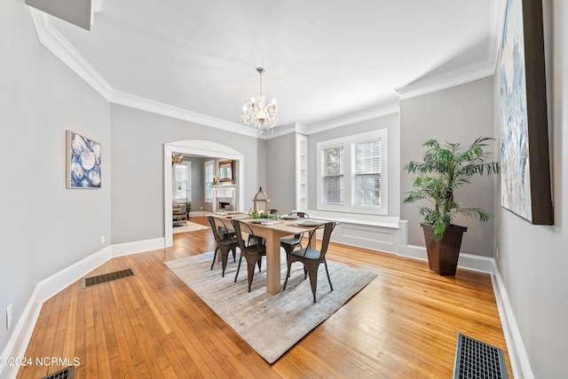 dining room featuring a chandelier, light hardwood / wood-style floors, and crown molding