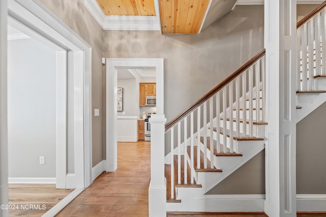 stairs with hardwood / wood-style flooring, crown molding, and wood ceiling