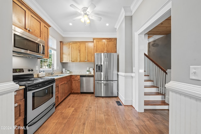 kitchen featuring light wood-type flooring, stainless steel appliances, ceiling fan, and ornamental molding