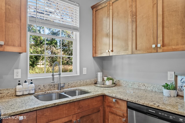 kitchen featuring dishwasher, light stone countertops, and sink