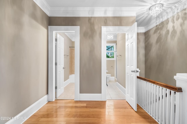 corridor featuring a notable chandelier, light hardwood / wood-style floors, and ornamental molding