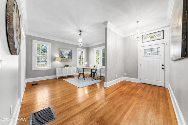 foyer entrance with light wood-type flooring, an inviting chandelier, and crown molding