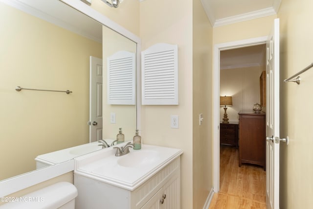 bathroom with toilet, vanity, wood-type flooring, and ornamental molding