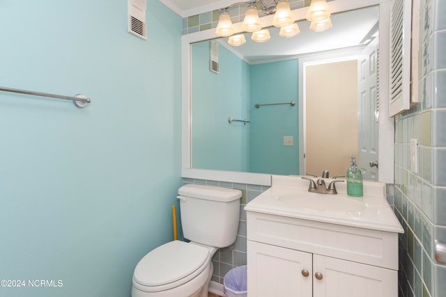 bathroom featuring vanity, toilet, ornamental molding, and tile walls